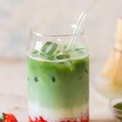 3 layers of strawberry puree, milk and matcha tea in a drinking glass.