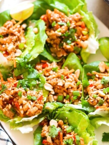 lettuce cups filled with ground chicken and toppings on a plate.