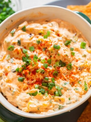 spicy corn dip in a bowl with nachos on the side.