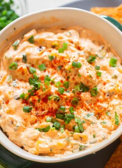 spicy corn dip in a bowl with nachos on the side.